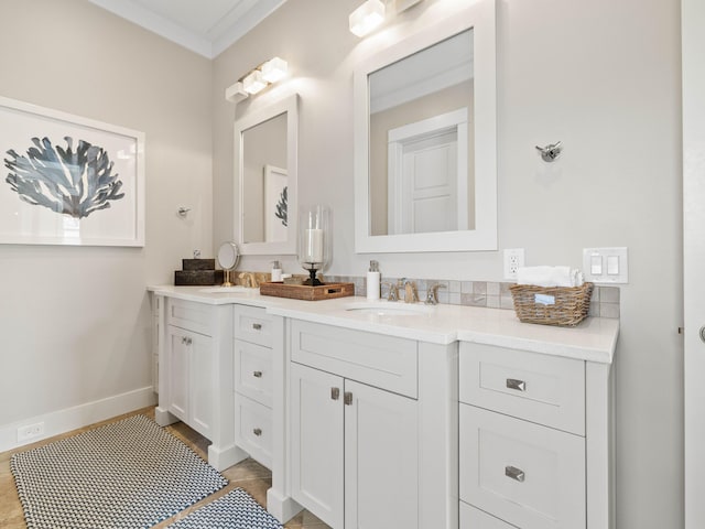 bathroom with double vanity, baseboards, a sink, and ornamental molding