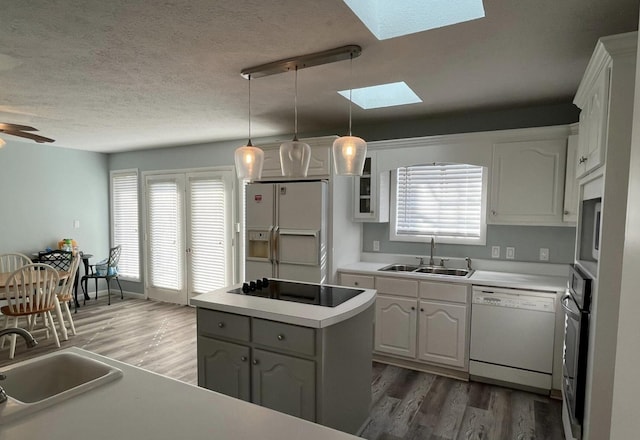 kitchen featuring sink, white cabinetry, a kitchen island, pendant lighting, and white appliances