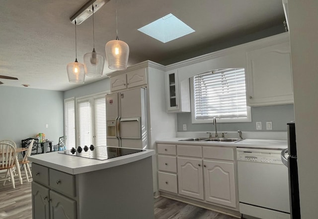 kitchen with sink, white appliances, white cabinetry, a center island, and decorative light fixtures