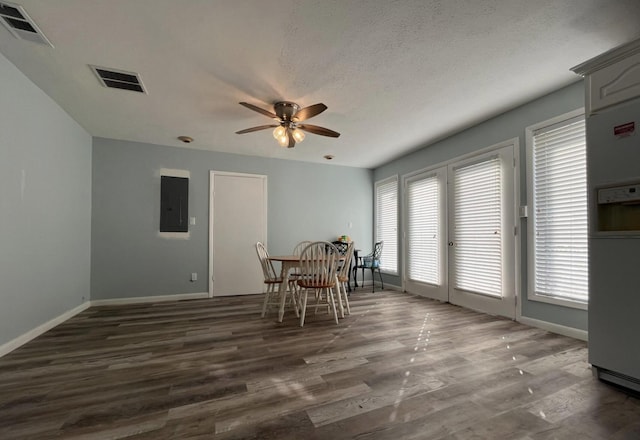 unfurnished dining area featuring dark hardwood / wood-style flooring, a textured ceiling, electric panel, and ceiling fan