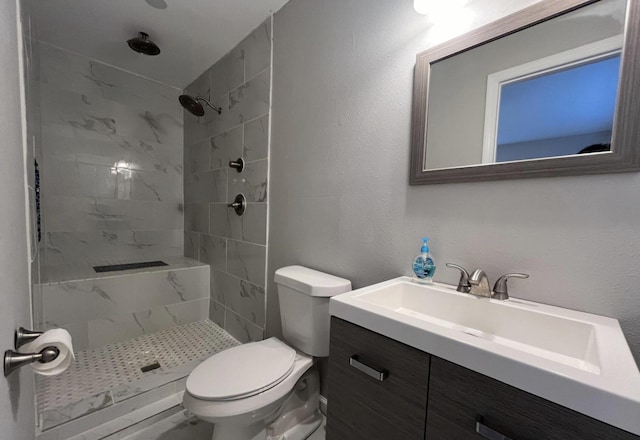 bathroom featuring vanity, toilet, and a tile shower