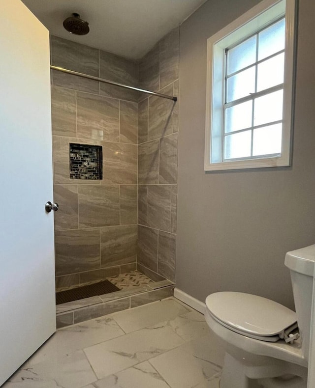 bathroom featuring tiled shower and toilet