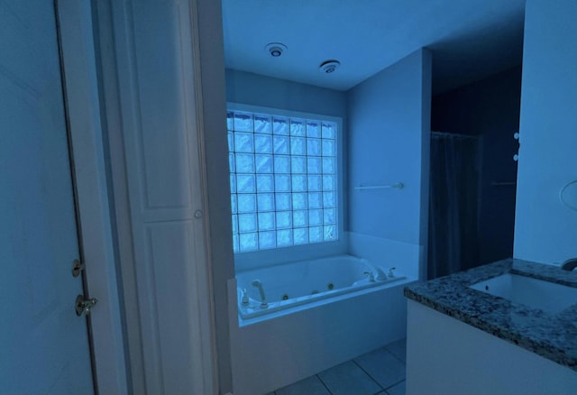 bathroom featuring tile patterned flooring, vanity, and tiled tub