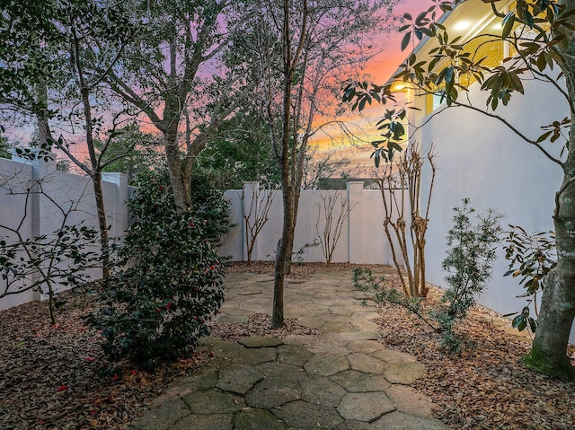 patio terrace at dusk featuring a fenced backyard