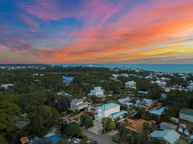 aerial view at dusk featuring a water view