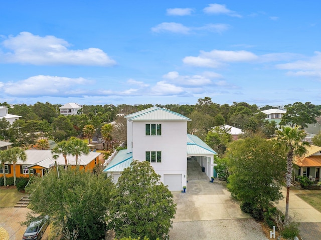 view of front facade featuring metal roof, an attached garage, driveway, stucco siding, and a carport