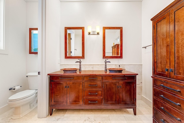 full bathroom featuring a sink, toilet, and double vanity