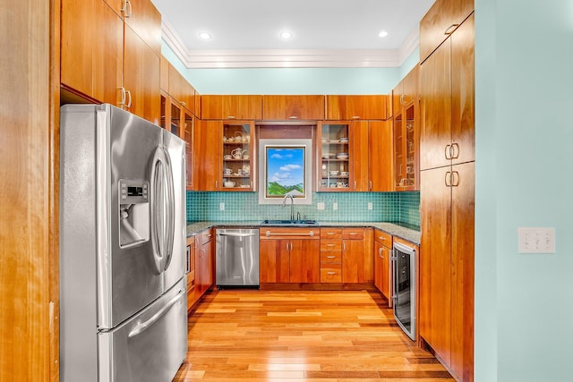 kitchen featuring wine cooler, tasteful backsplash, appliances with stainless steel finishes, brown cabinetry, and a sink