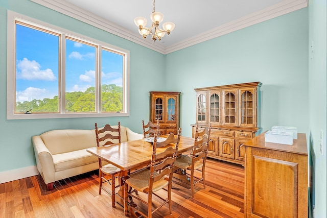 dining space with ornamental molding, light wood-type flooring, a notable chandelier, and baseboards