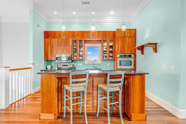 kitchen with stainless steel appliances, tasteful backsplash, brown cabinetry, and a center island