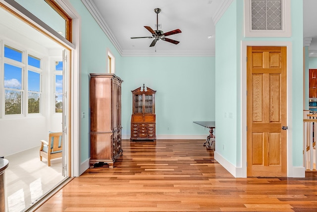 interior space with light wood finished floors, baseboards, visible vents, and crown molding