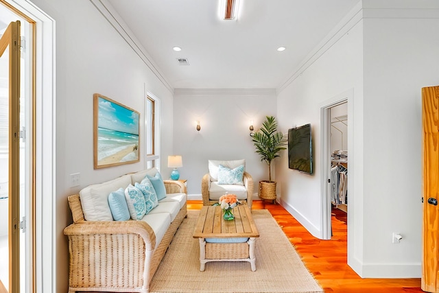 living area featuring visible vents, baseboards, light wood-style flooring, ornamental molding, and recessed lighting