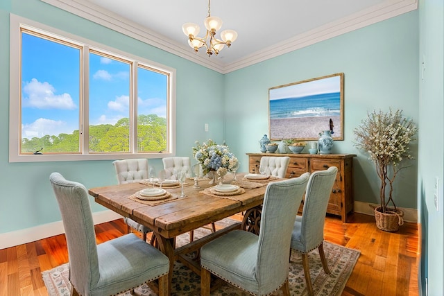 dining room featuring light wood-style floors, baseboards, crown molding, and an inviting chandelier