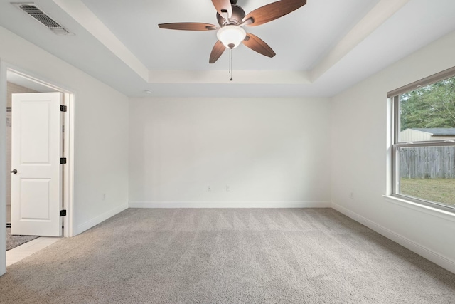 carpeted empty room featuring ceiling fan and a tray ceiling