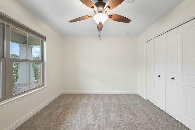 unfurnished bedroom featuring light carpet, a closet, and ceiling fan