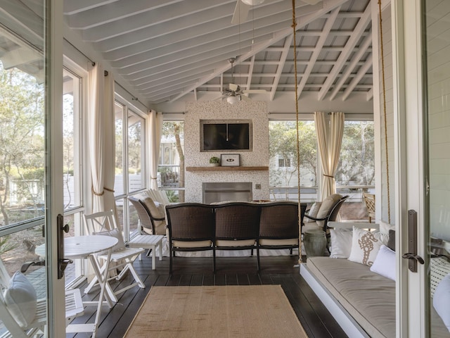 sunroom / solarium with vaulted ceiling with beams, a ceiling fan, and a wealth of natural light