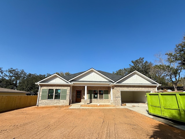 view of front of home with an attached garage, fence, concrete driveway, and brick siding