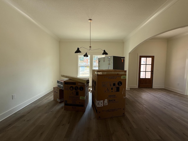 unfurnished dining area with arched walkways, a textured ceiling, dark wood finished floors, and baseboards