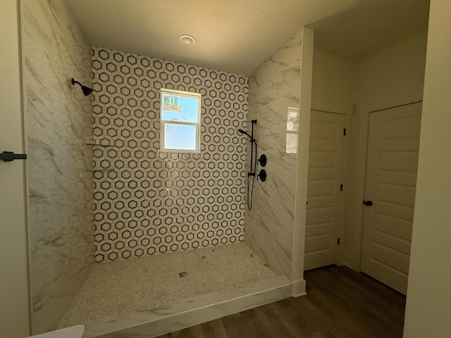 bathroom featuring a textured ceiling, tiled shower, and wood finished floors