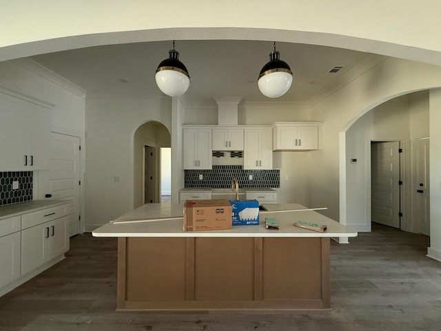 kitchen featuring ornamental molding, arched walkways, and white cabinetry