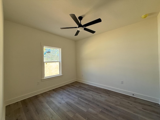 unfurnished room featuring a ceiling fan, dark wood-style flooring, and baseboards