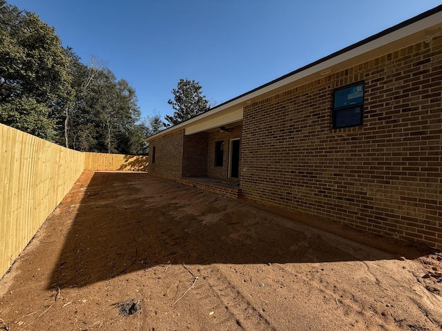 view of side of home with a patio area, a fenced backyard, and brick siding