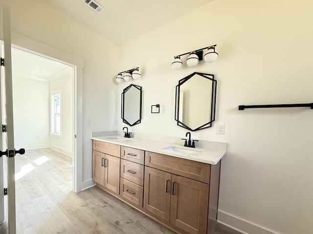 bathroom featuring wood finished floors, a sink, visible vents, and baseboards