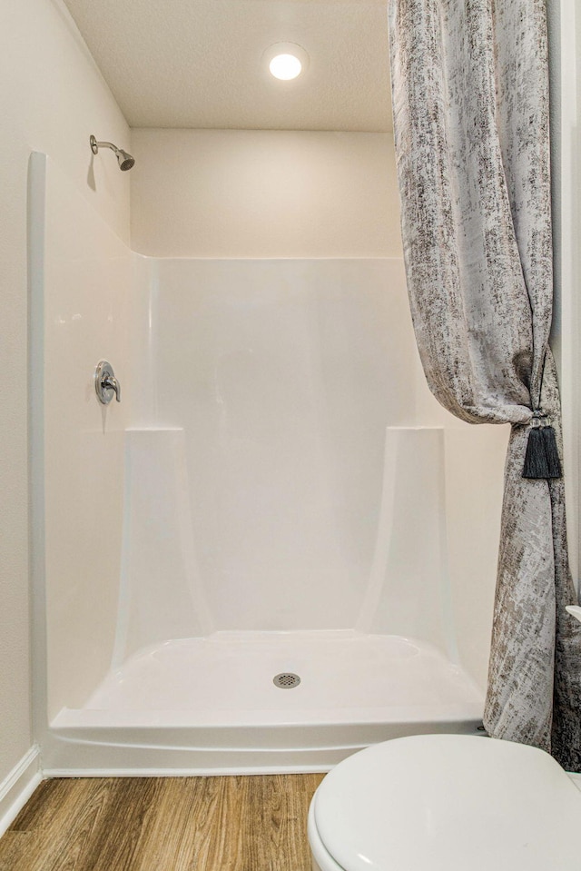 bathroom with a textured ceiling, wood-type flooring, a shower with curtain, and toilet