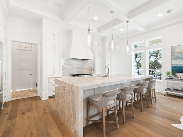 kitchen featuring light wood-style floors, backsplash, custom exhaust hood, and light stone countertops