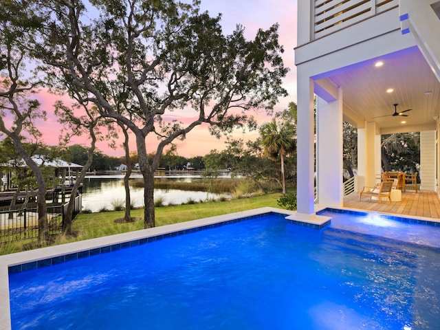 59 Arboleda Dr, Santa Rosa Beach, FL 32459 - pool at dusk featuring an outdoor pool, a water view, ceiling fan, and fence
