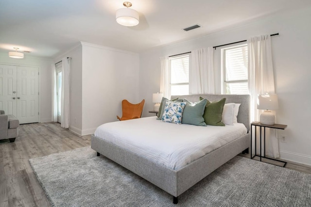 bedroom featuring ornamental molding and light hardwood / wood-style floors