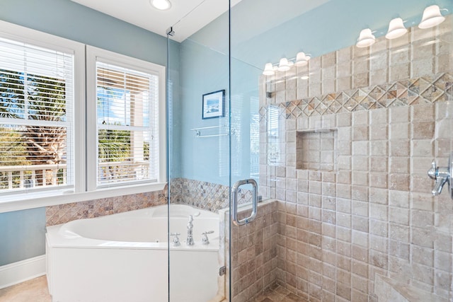 bathroom featuring a stall shower, a garden tub, and baseboards