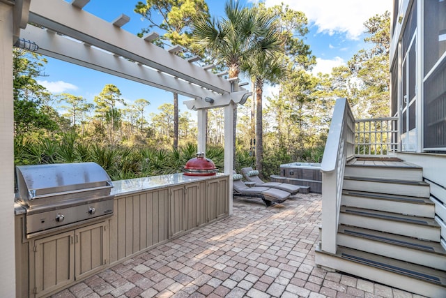 view of patio / terrace with a pergola, an outdoor kitchen, a grill, and a hot tub