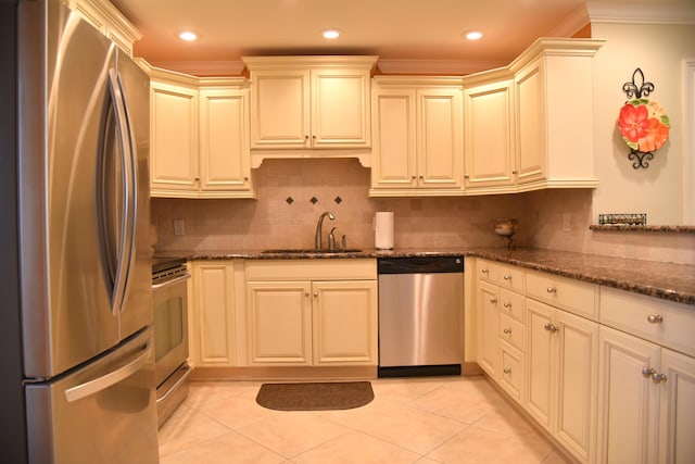 kitchen with sink, ornamental molding, stainless steel appliances, and dark stone counters