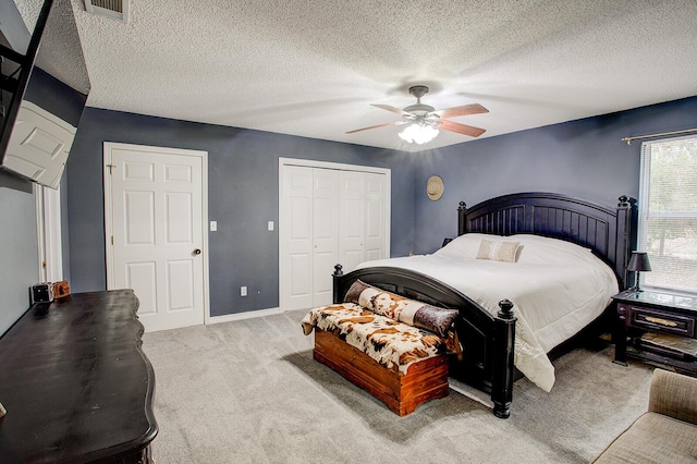 bedroom with light colored carpet, a textured ceiling, ceiling fan, and a closet