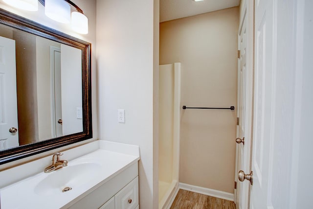 bathroom with walk in shower, vanity, and hardwood / wood-style floors