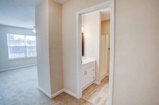 corridor featuring light colored carpet and a textured ceiling