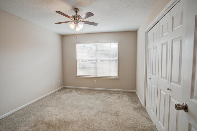 unfurnished bedroom with ceiling fan, light colored carpet, a closet, and a textured ceiling