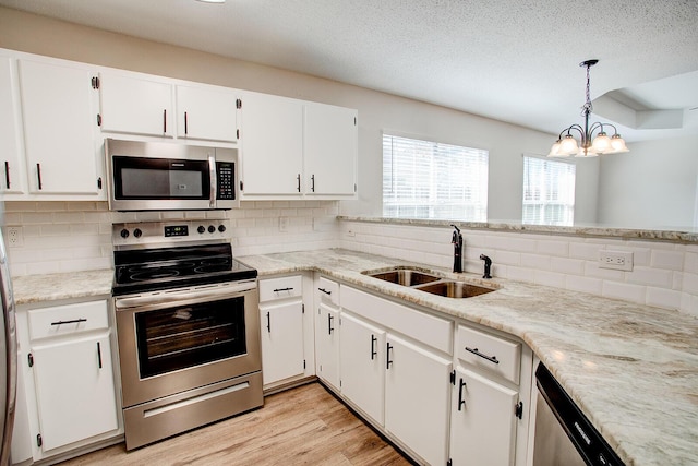 kitchen featuring sink, white cabinetry, decorative light fixtures, light hardwood / wood-style flooring, and stainless steel appliances