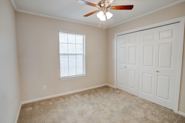 unfurnished bedroom featuring ornamental molding, light carpet, ceiling fan, and a closet