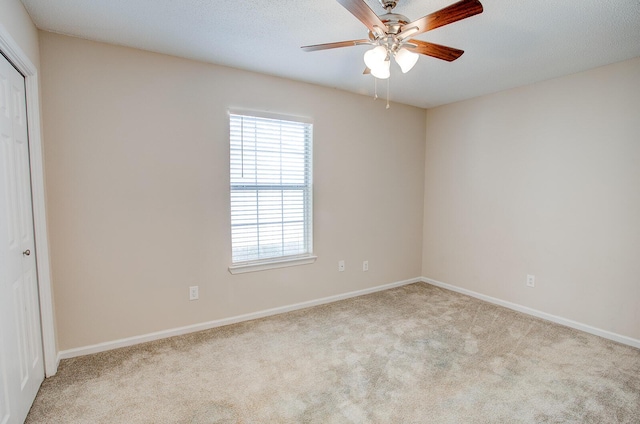 spare room featuring light carpet, a textured ceiling, and ceiling fan