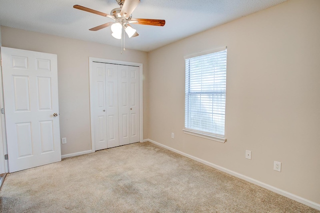 unfurnished bedroom featuring ceiling fan, light colored carpet, and a closet