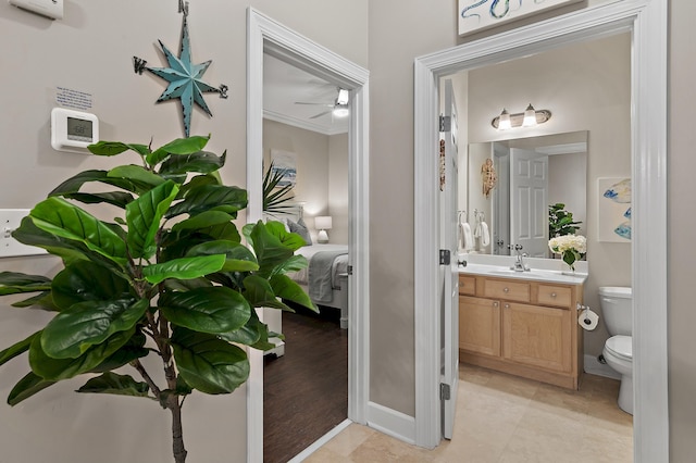 bathroom with crown molding, toilet, a ceiling fan, vanity, and baseboards