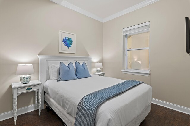 bedroom featuring dark wood-style flooring, crown molding, and baseboards