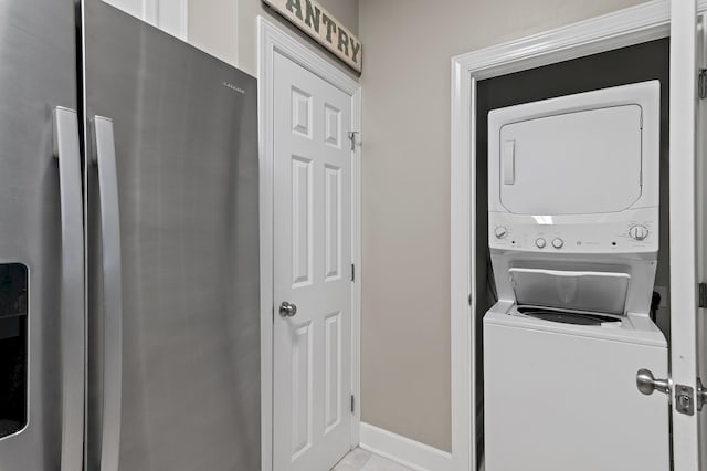 clothes washing area featuring baseboards, laundry area, and stacked washer / drying machine