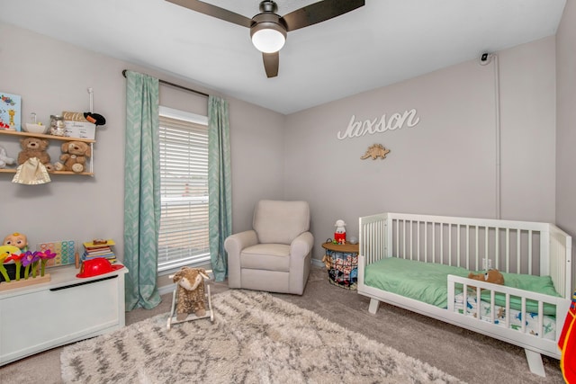 bedroom with a crib, ceiling fan, and carpet flooring