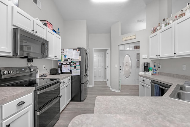 kitchen with dishwashing machine, stainless steel fridge, light hardwood / wood-style flooring, double oven range, and white cabinets