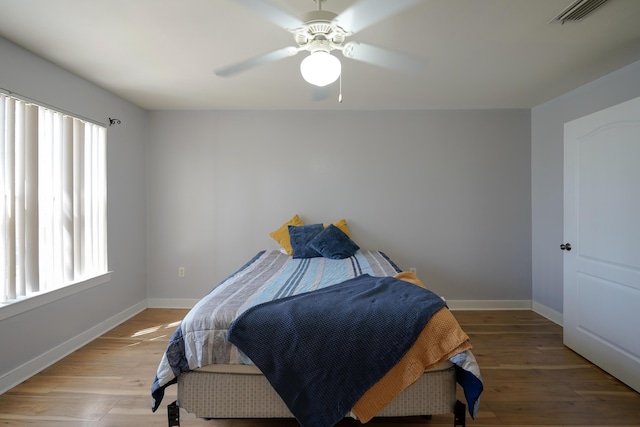 bedroom featuring light wood finished floors, visible vents, ceiling fan, and baseboards