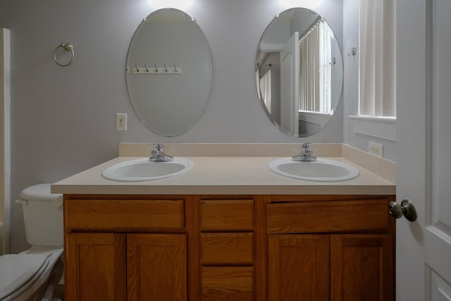 full bath with double vanity, toilet, and a sink