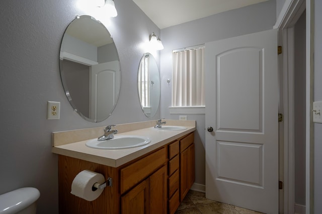 bathroom featuring double vanity, toilet, tile patterned floors, and a sink